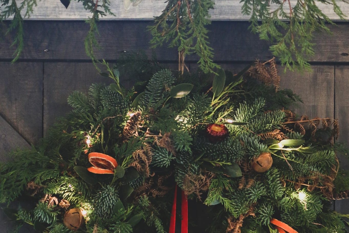 A finished Christmas wreath on a door with fairy lights and dried orange slices